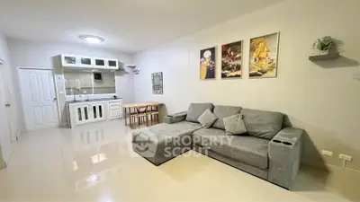 Spacious living room with modern gray sofa and open kitchen layout, perfect for cozy gatherings.