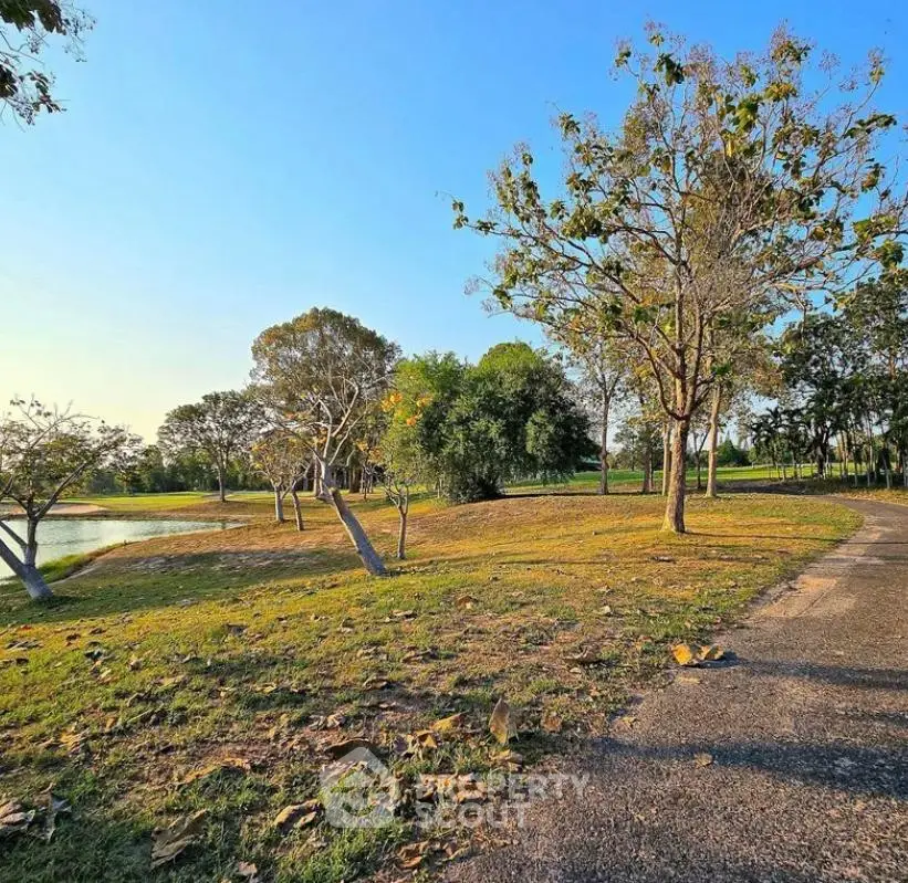 Scenic view of a serene park with lush greenery and a tranquil pond, perfect for outdoor relaxation.
