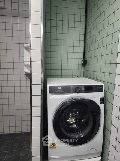 Modern bathroom with washing machine and tiled walls, perfect for convenient living.