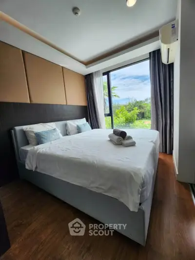 Luxurious bedroom with large window offering stunning garden view, featuring modern decor and cozy ambiance.