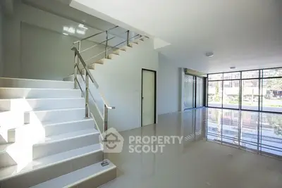 Spacious modern interior with large windows and sleek staircase, perfect for natural light lovers.