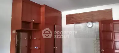 Spacious bedroom with wooden built-in wardrobes and a wall clock, ideal for organized living.