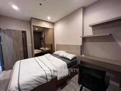 Modern bedroom with cozy bed, built-in wardrobe, and study desk in stylish apartment.