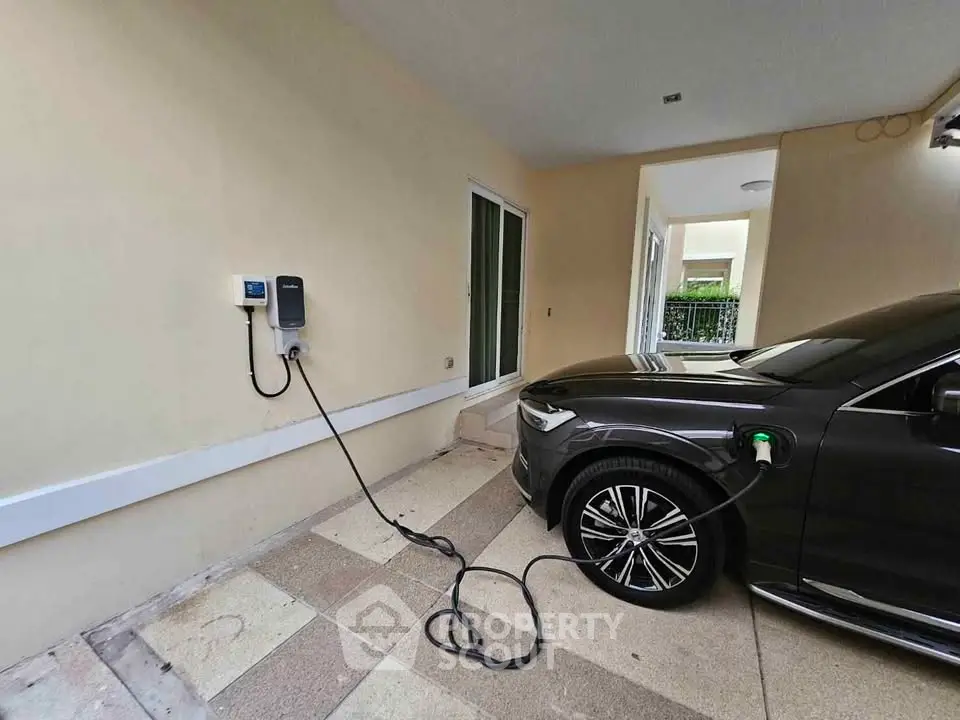 Modern home with electric vehicle charging station in covered parking area, showcasing eco-friendly living.