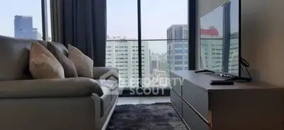 Modern living room with city view, featuring sleek furniture and large windows.