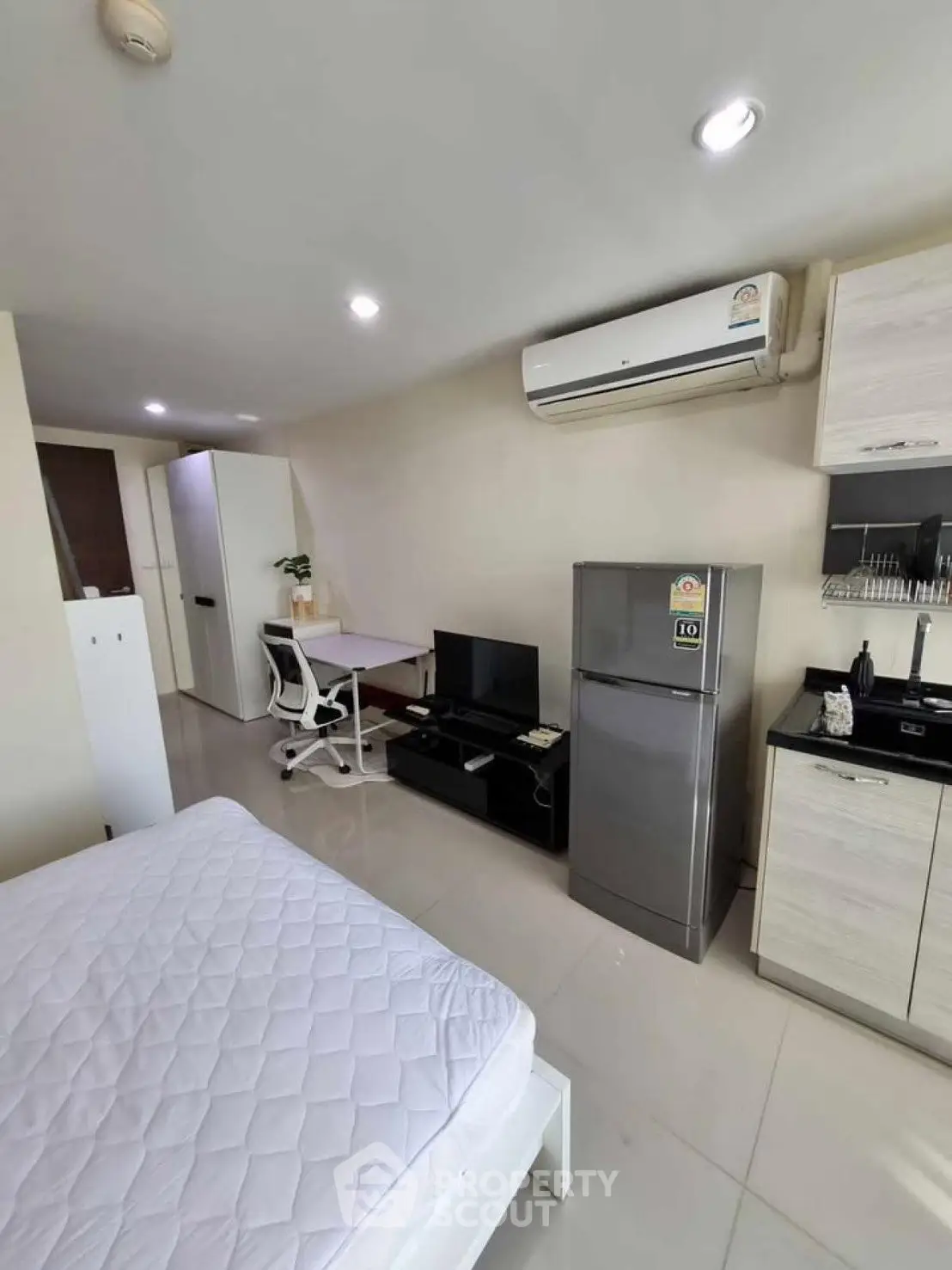 Modern studio apartment with sleek furnishings and air conditioning, featuring a compact kitchen and cozy living area.