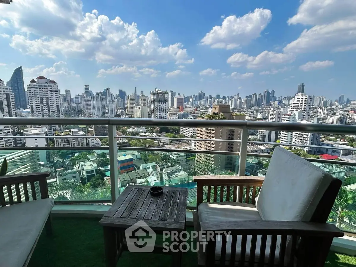 Stunning cityscape view from a high-rise balcony with cozy seating area.