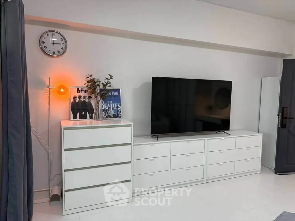 Modern living room with sleek white furniture and large TV setup