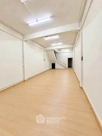 Spacious open-plan interior with wooden flooring and staircase, ideal for versatile use.