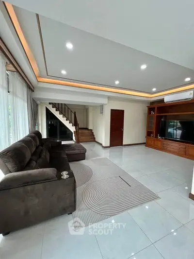 Spacious modern living room with elegant staircase and cozy seating area.