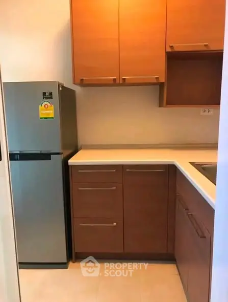 Modern kitchen with sleek cabinets and stainless steel fridge in a cozy apartment.