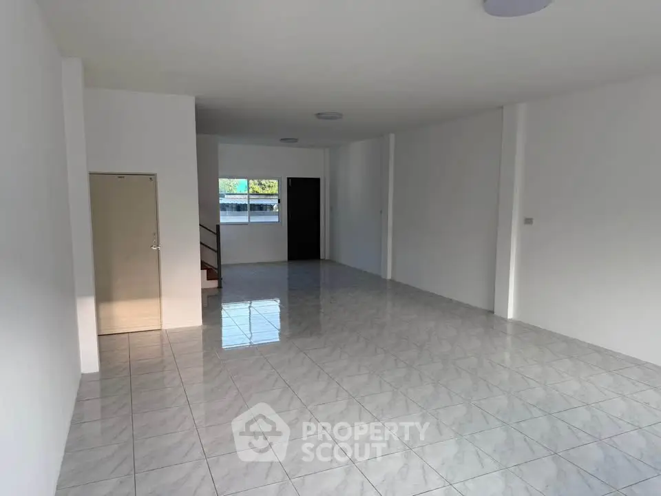 Spacious open-plan living area with tiled flooring and ample natural light.