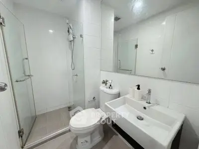 Modern bathroom with glass shower and sleek white fixtures in a contemporary apartment.