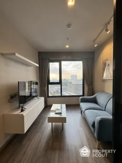 Modern living room with city view, sleek furniture, and large window for natural light.