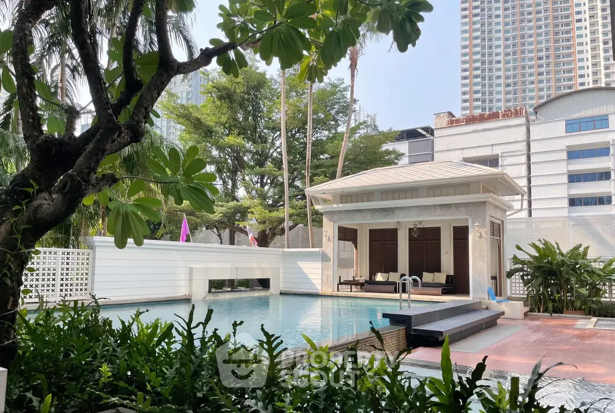 Luxurious poolside view with lush greenery and modern architecture in urban setting.