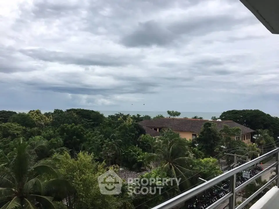 Stunning balcony view overlooking lush greenery and distant ocean horizon.