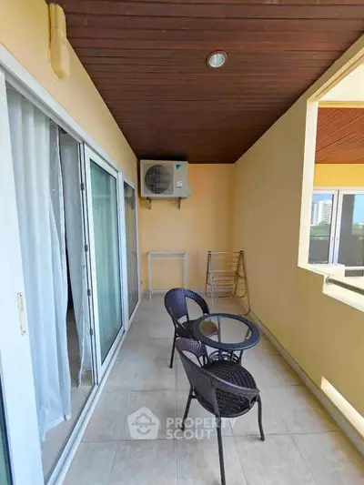 Spacious balcony with seating area and air conditioning unit, perfect for relaxation.