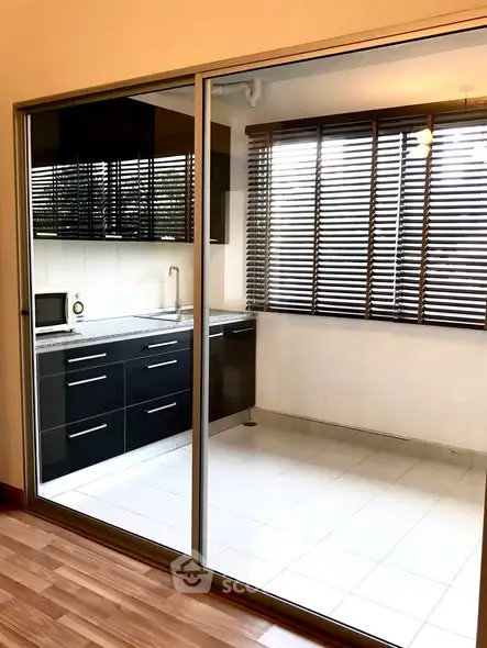 Modern kitchen with sleek black cabinets and large windows for natural light.