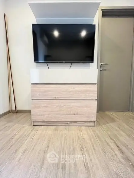 Modern living room with sleek TV setup and stylish wooden flooring.