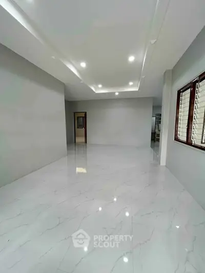 Spacious modern living room with sleek marble flooring and recessed lighting.