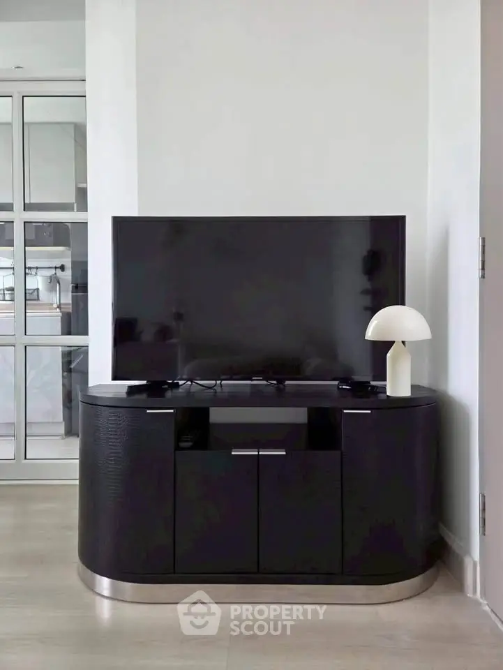 Modern living room with sleek TV stand and stylish lamp, showcasing contemporary interior design.