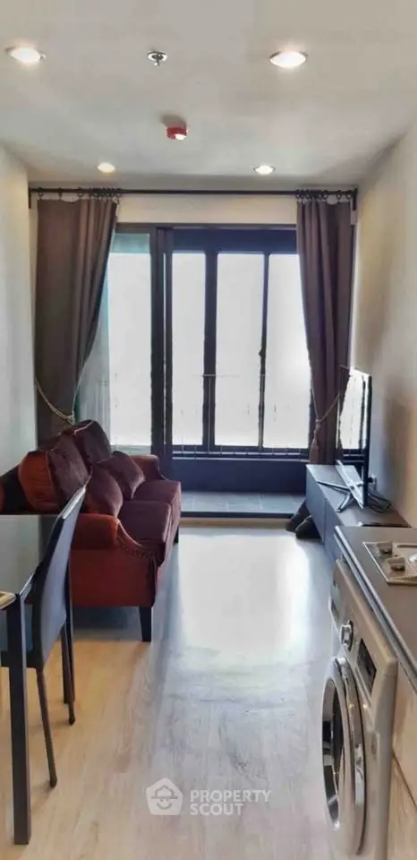 Modern living room with washing machine and balcony view, featuring cozy seating and sleek design.