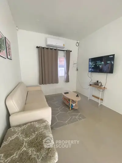 Cozy living room with modern decor, featuring a wall-mounted TV and comfortable seating.