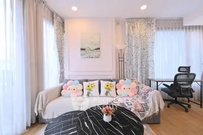 Charming living room with cozy sofa, floral decor, and elegant curtains, perfect for relaxation and work-from-home setup.