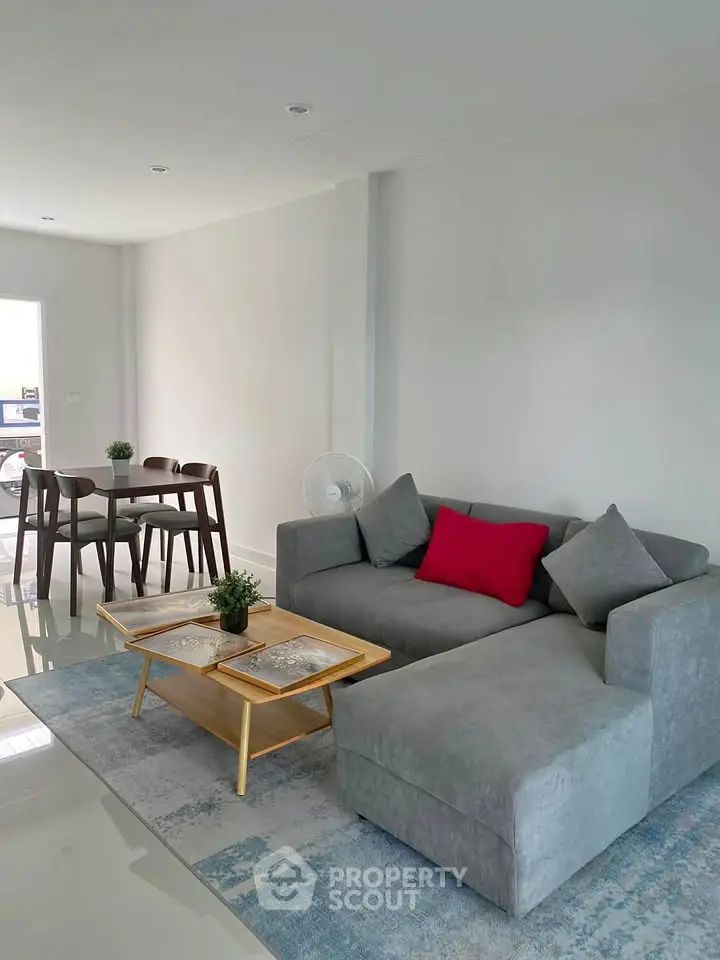 Modern living room with stylish gray sofa and wooden dining set in open layout