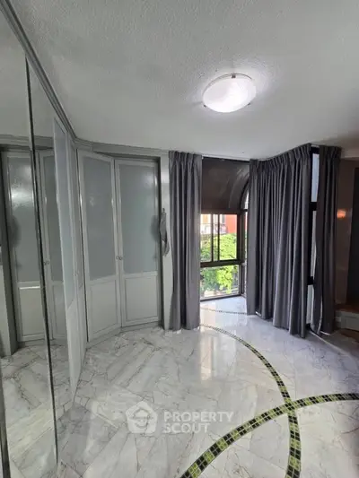 Elegant bedroom with marble flooring and large windows offering natural light.