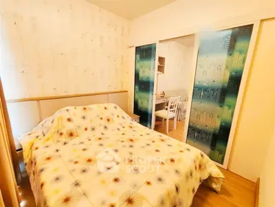 Cozy bedroom with stylish decor and sliding doors leading to a dining area, perfect for modern living.