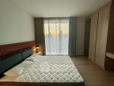 Modern bedroom with large window and city view, featuring a stylish bed and built-in wardrobe.