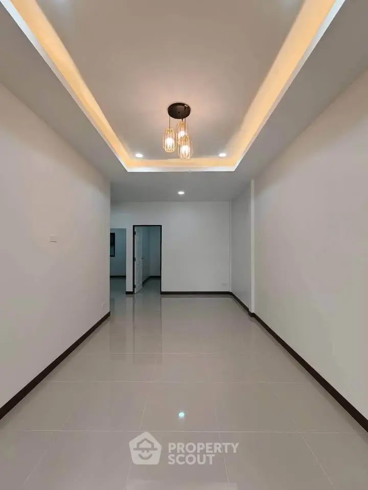 Spacious modern living room with elegant lighting and sleek tile flooring, perfect for contemporary living.
