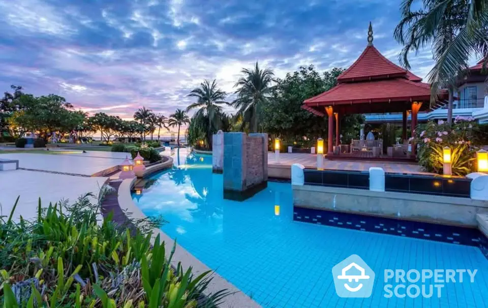 Luxurious tropical resort pool with stunning sunset view and lush greenery.