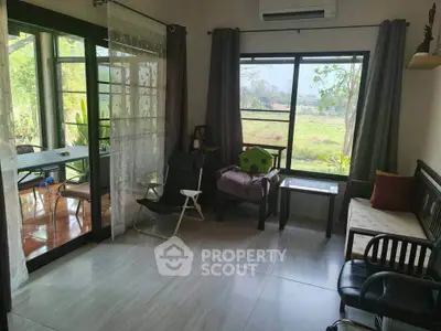Charming living room with large windows and garden view, perfect for relaxation and natural light.