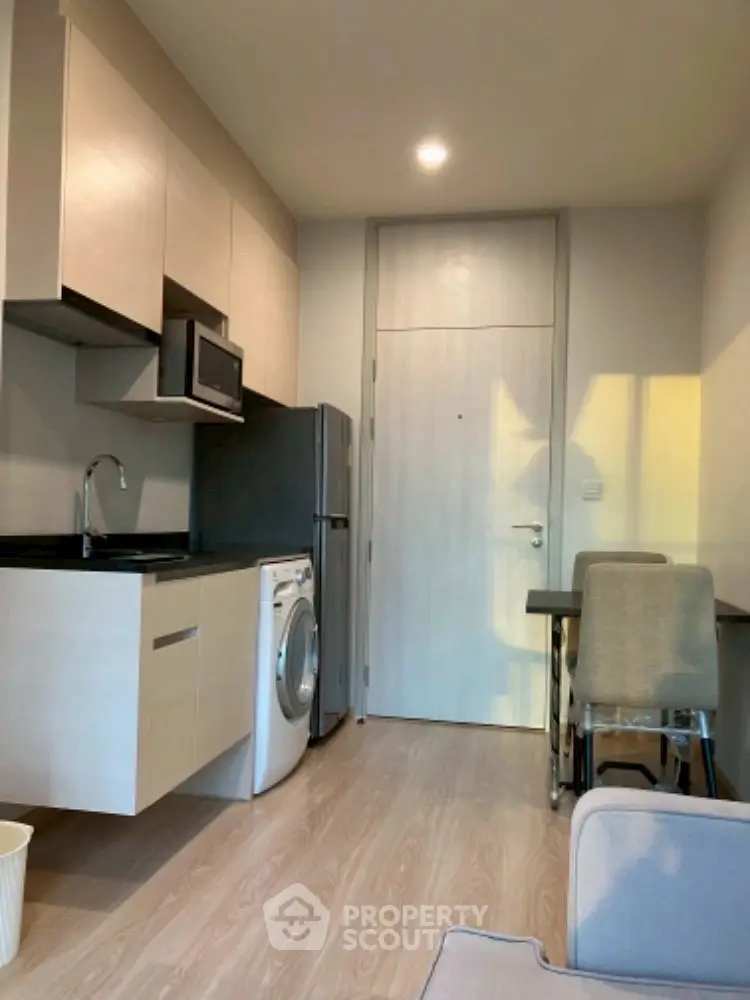 Modern compact kitchen with washing machine and dining area in cozy apartment.