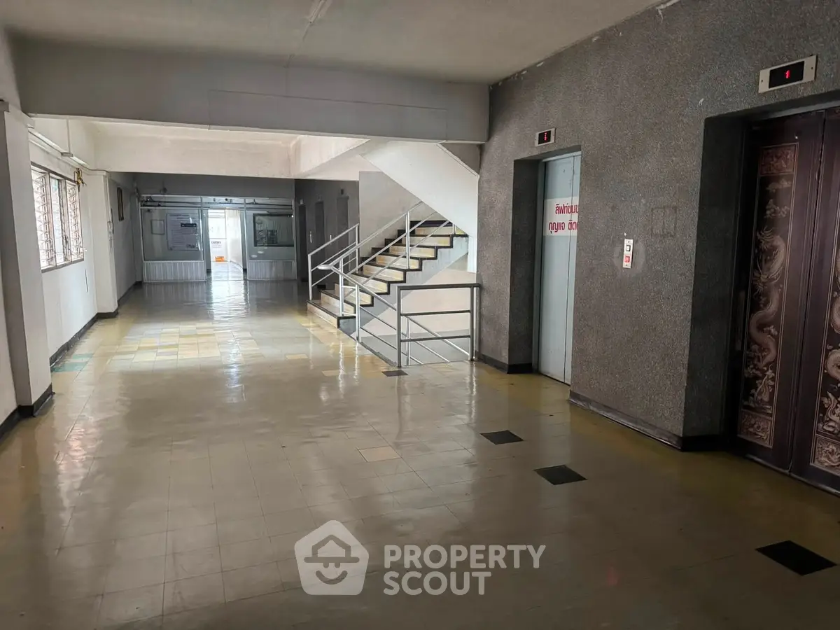 Spacious building corridor with elevators and stair access, ideal for commercial or residential use.