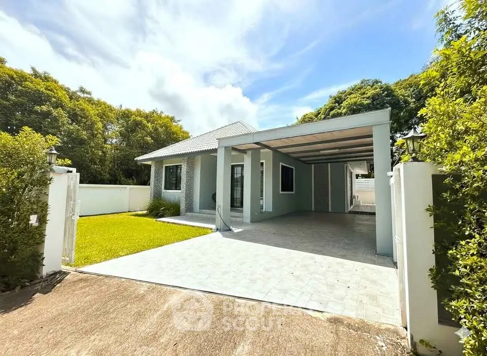Charming single-story home with spacious driveway and lush greenery, perfect for serene living.