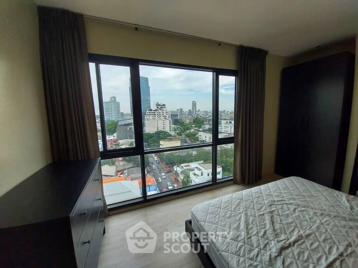 Spacious bedroom with stunning city view from large windows in modern apartment.