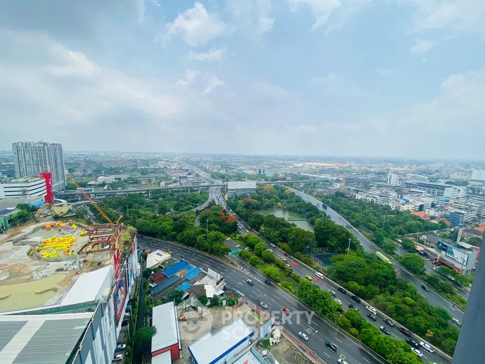 Stunning cityscape view from high-rise building with lush greenery and urban skyline.