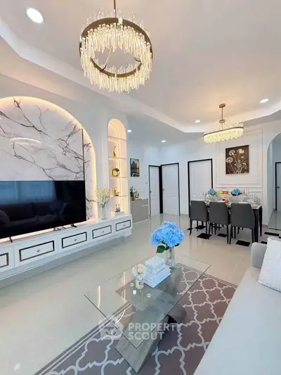 Luxurious living room with elegant chandeliers and modern decor, featuring a marble accent wall and stylish furniture.