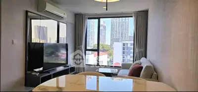 Modern living room with city view, featuring sleek furniture and large windows for natural light.