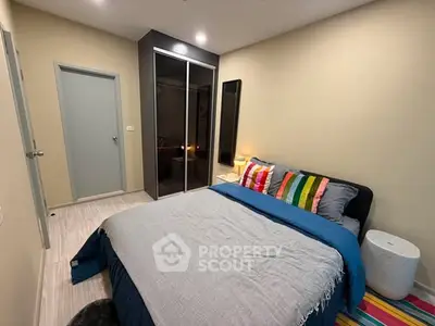 Cozy bedroom with modern decor and colorful accents, featuring a comfortable bed and sleek wardrobe.