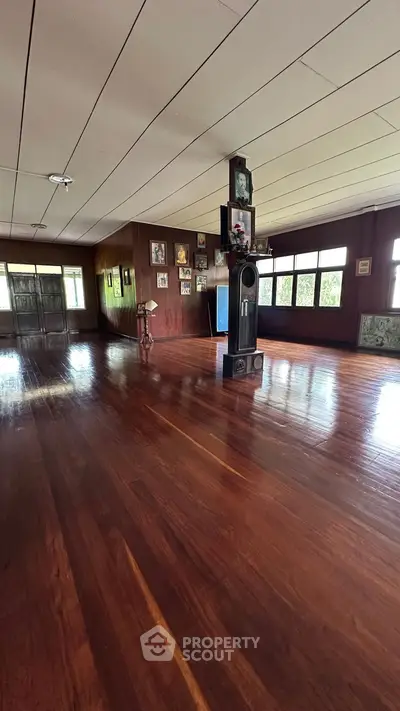 Spacious wooden-floored room with vintage decor and large windows offering natural light.
