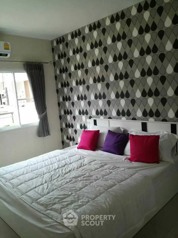 Modern bedroom with stylish wallpaper and colorful pillows in a cozy apartment.
