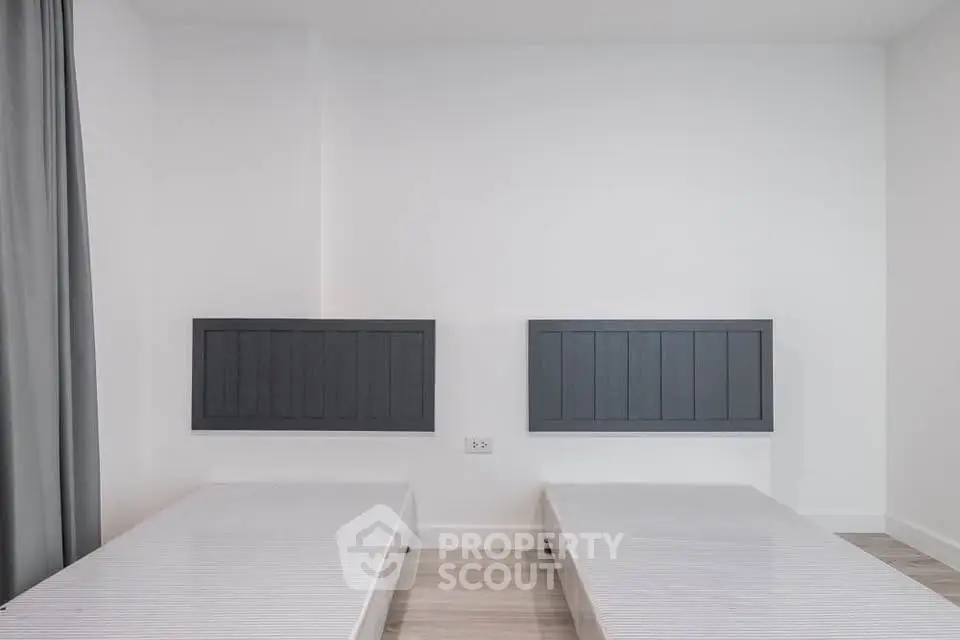 Minimalist bedroom with twin beds and modern headboards in a bright, airy space.
