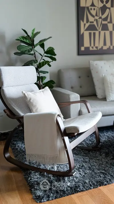 Cozy living room with modern rocking chair and plush sofa on a stylish rug.