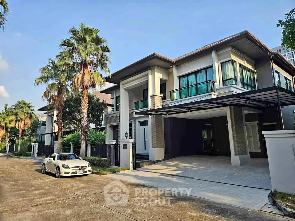 Luxurious modern house with spacious driveway and lush palm trees in a serene neighborhood.