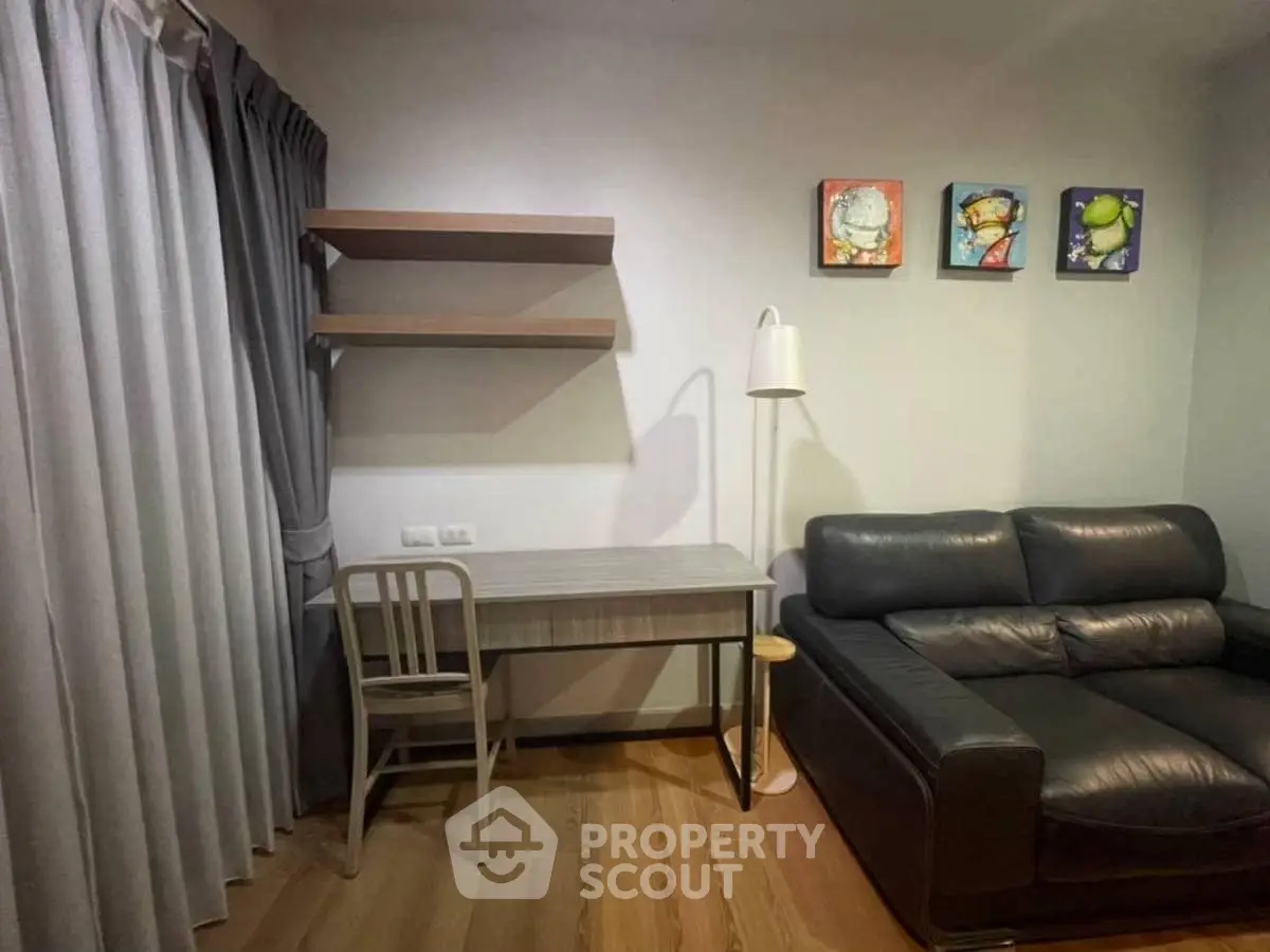 Cozy living room with modern decor, featuring a sleek black sofa and stylish wooden desk.