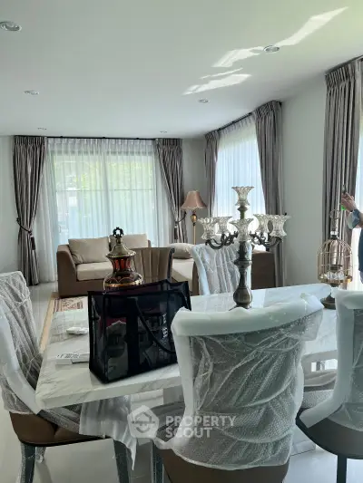 Elegant living room with natural light, featuring a stylish dining area and cozy seating, perfect for modern living.